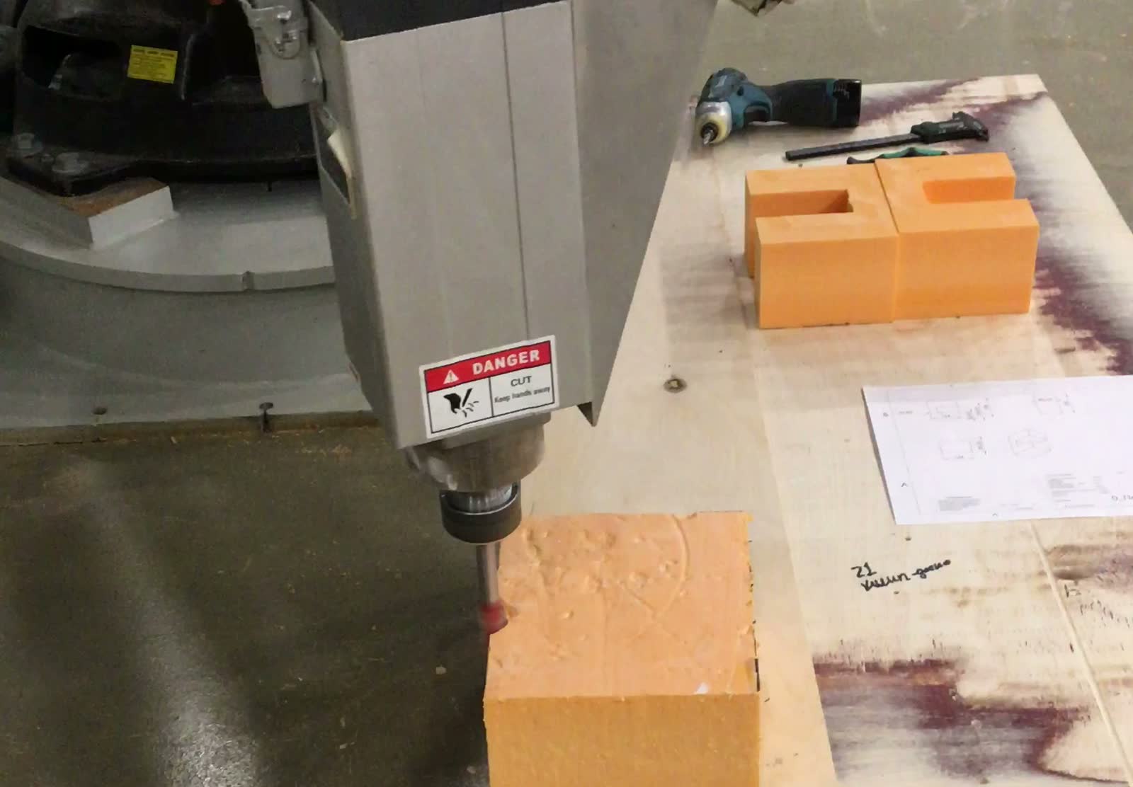 Robot spindle cutting a test block next to the working drawing